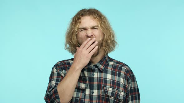 Slow Motion of Unamused Blond Man with Wavy Long Hair and Beard Yawning and Covering Mouth with Hand