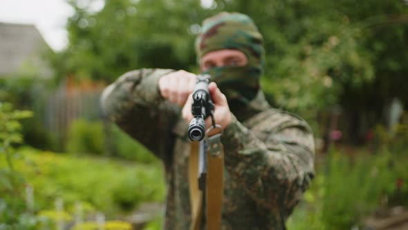 Closeup of a Masked Soldier Preparing to Fire and Pointing the Machine Gun Towards the Camera alt