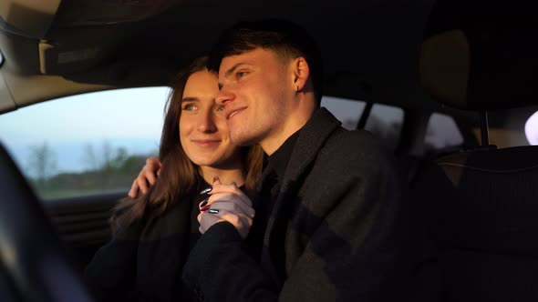 Romantic Couple Pretty Lovers Looking at Each Other with Tenderness and Sitting in Car at Sunset alt