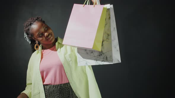 Positive Afro Girl Posing for Camera with Shopping Bags alt
