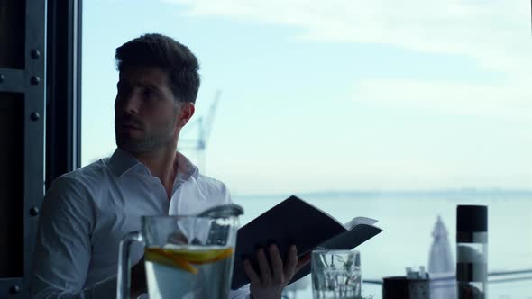 Focused Entrepreneur Looking Cafe Dinner Menu on Cozy Restaurant Terrace alt