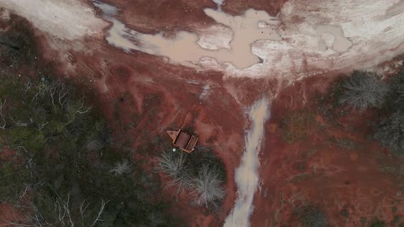 A high view looking down at a old rusted piece of  mining equipment surrounded by the red rich soil alt