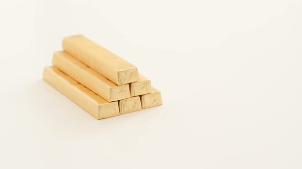 Golden foil wrapped chocolate bars on white surface 4k 2160p UltraHD footage - Wrapped in gold color alt