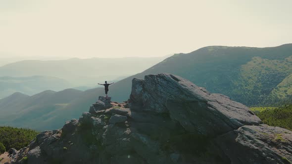 Hiker Stands on a Rock Looking to the Future at Sunset alt