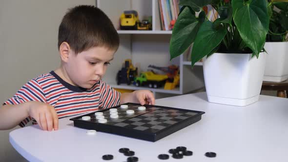 A Child of 4 Years Places Checkers on the Board Prepares for a Board Game alt