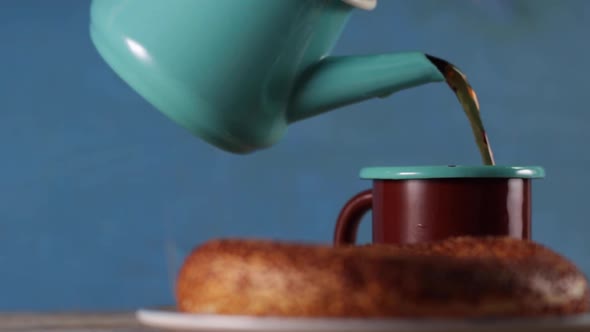 Pouring Tea From a Kettle in a Cup alt