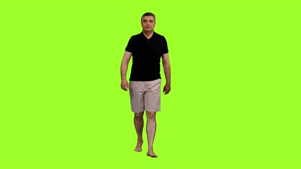 Man Tourist in Gray Shorts and Black T-shirt Walks Barefoot 
