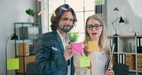 Man and Woman Standing Behind the Glass wall in Office Room and Brainstorming Ideas alt