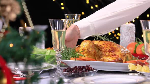 Hands Serving Roasted Chicken on Christmas Festive Table