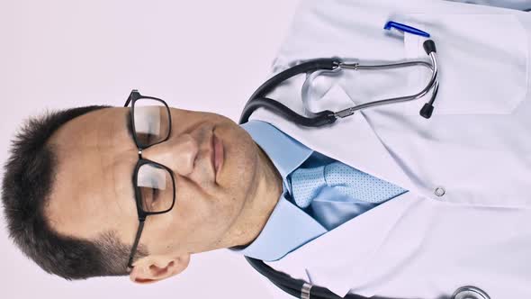 Vertical Shot Serious Male Doctor in Lab Coat and Stethoscope Puts on Latex Protective Gloves