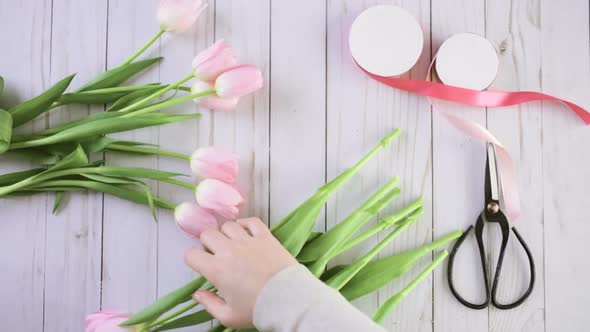 Step by step. Florist wrapping pink tulips in bouquet alt