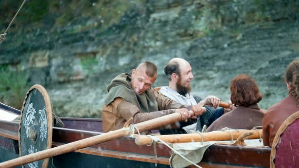 Vikings Sail on an Old Ship with a Lowered Sail on a Quiet River alt