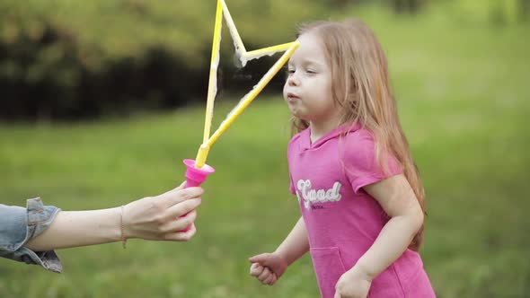 Confident Playful Little Cute Girl Blowing Huge Air Soap Bubble Blower Medium Close-up