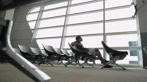 The young, handsome man sitting alone at the airport in a waiting room alt