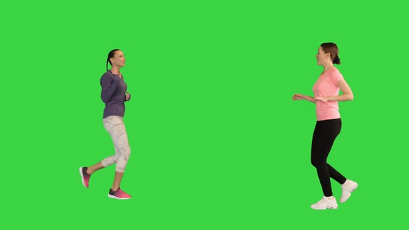 Two Women Running Towards Each Other and Waving Greeting on a Green Screen Chroma Key