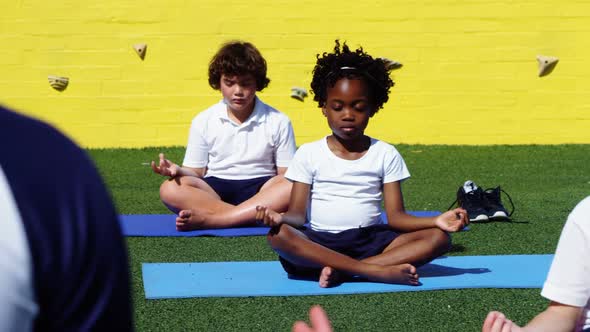 Yoga instructor instructing children in performing yoga alt