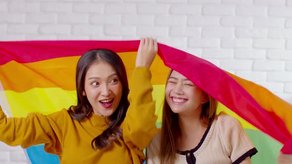 LGBTQ Asian lesbian young couple smiling holding pride flag happiness with love together alt
