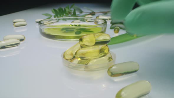Lab Scientist Placing Oil Capsule in Dish with Beauty Supplements alt