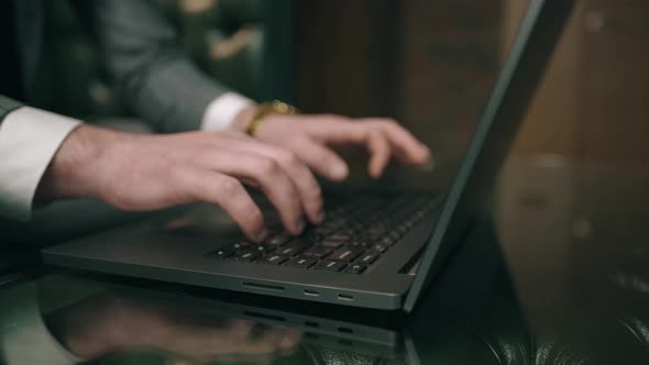 Businessman in Suit Is Sitting and Using Laptop Indoor alt