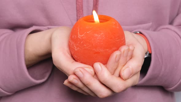 Woman or Girl Holding in Hands Red Round Burning Candle