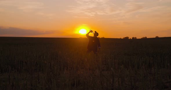 Drunken Farmer Drinking Alcohol on Field During Sunset alt