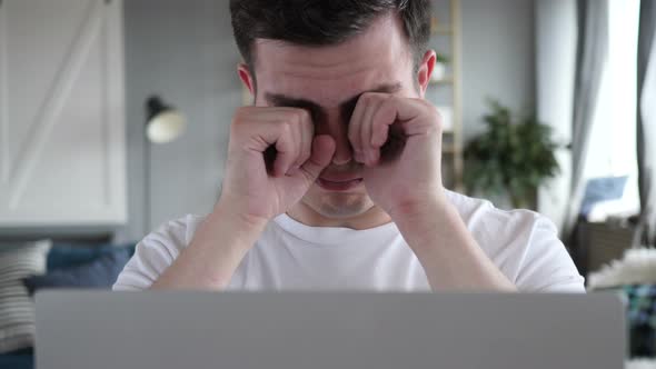 Tired Man Rubbing Eyes while working on Laptop alt