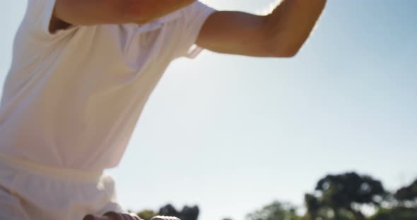 Wicket keeper collecting cricket ball behind stumps on cricket field alt