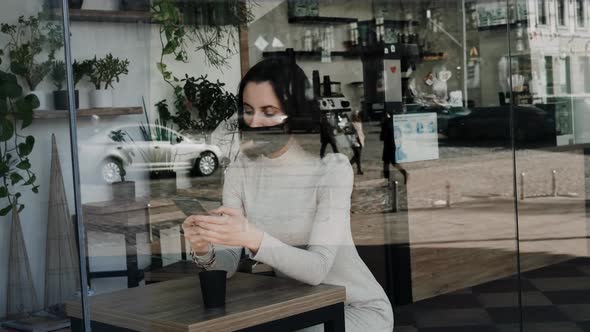 Young Woman with Black Medical Mask Sending Text Message Using Smartphone alt