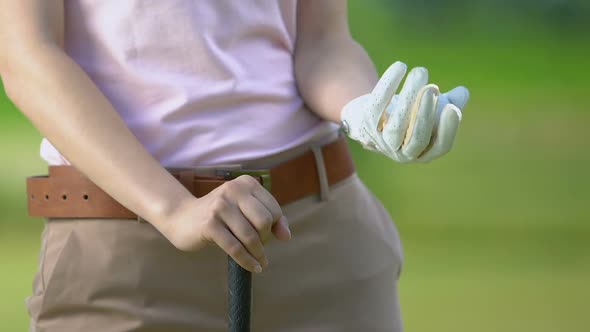 Female Golf Player Holding Ball and Club Waiting for Opponent on Golf Course alt