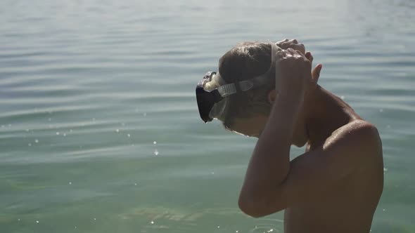 The Teenager Wears a Swimming Mask and Dives Into the Water.