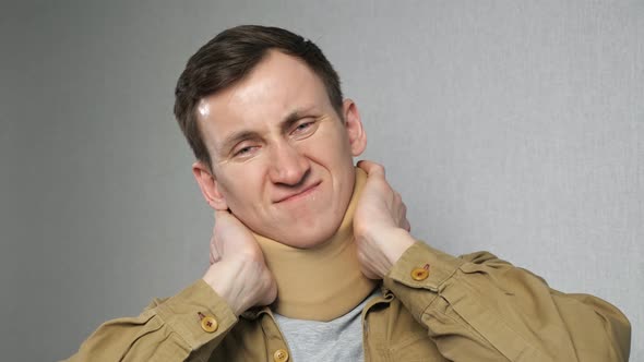 Man Tries to Knead Neck Wearing Bandage on Grey Background alt