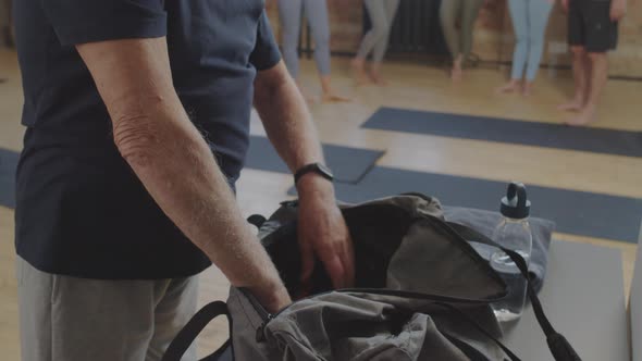 Senior Man Unpacking Bag in Yoga Studio alt