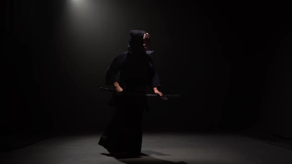 Kendo Fighter Performing Martial Art with Katana Sword at Dark Studio Under Spotlight. alt