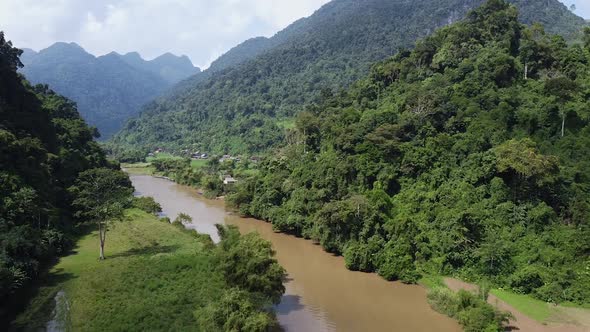 A Tourist Boat Sails Along the River Between Mountains and Green Forests in Asia Around the Jungle