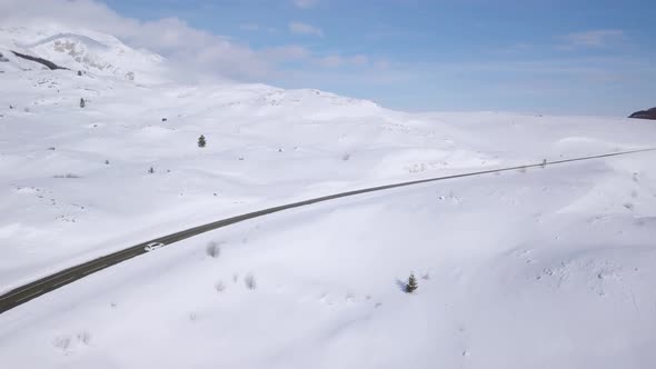 Aerial view of a car on winter road in the forest. Winter landscape countryside in Montenegro alt