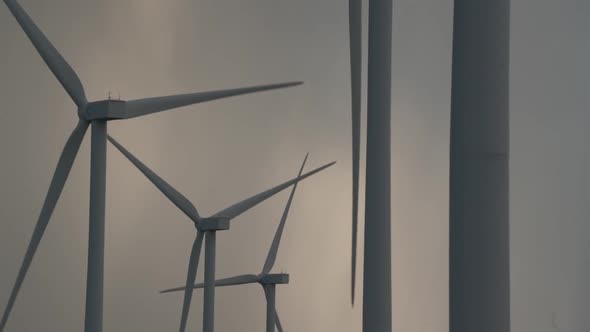 Large Windmill Silhouettes with Blades Rotating in Grey Sky