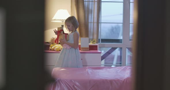 Little Caucasian Girl Holding Casket and Taking Something Red Treasure From It alt