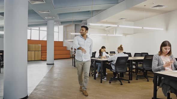 Young Male is Smiling and Dancing Clapping Hands Walking Along Modern Office with Diverse Colleagues alt