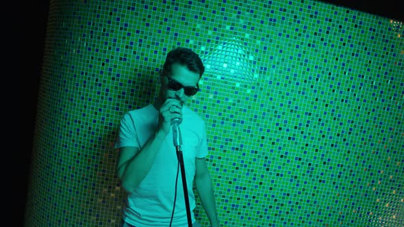 Mature Man with Sunglasses and White Tshirt Dances and Sings Holding Microphone
