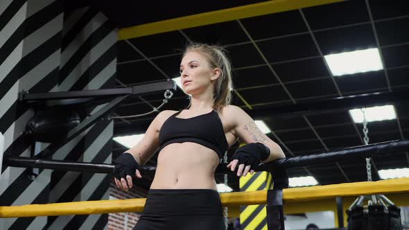 Portrait of a Slender Female Athlete Leaning on a Rope