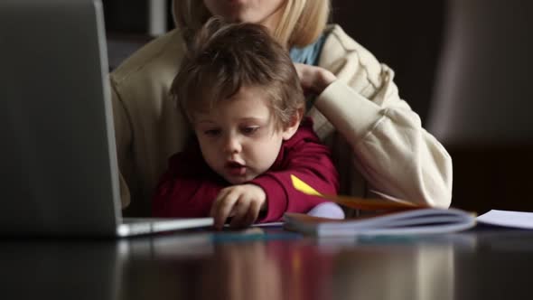 Little boy play with pencils while mother is working at home alt
