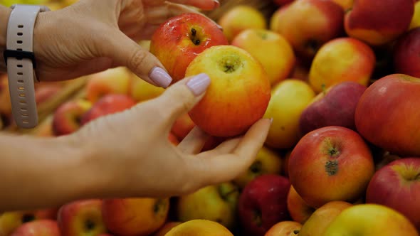 Closeup of Female Hands Picking Apples in the Supermarket