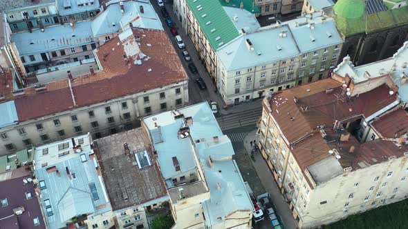 Aerial of European buildings and people walking the streets of Lviv Ukraine with cars parked on the alt