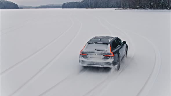 Cinematic Shot of Grey Station Wagon Car Driving on a Snowy Lake