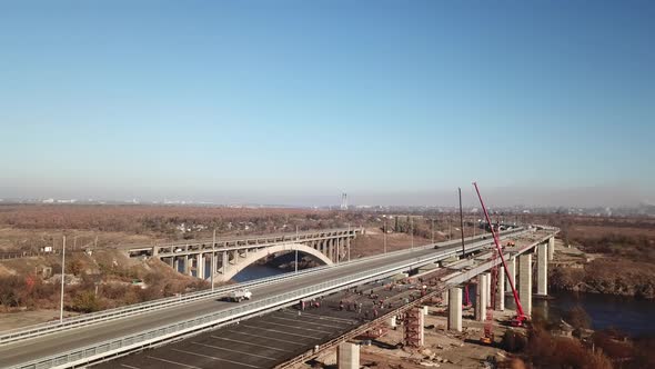 Aerial shot of a bridge with cars traveling along the road and carrying goods. alt