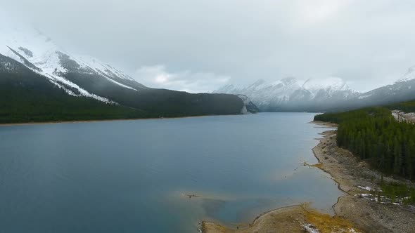 Bird's-eye view of a mirror Spray Lakes Reservoir at the foot of snowy mountains in Alberta, Canada  alt