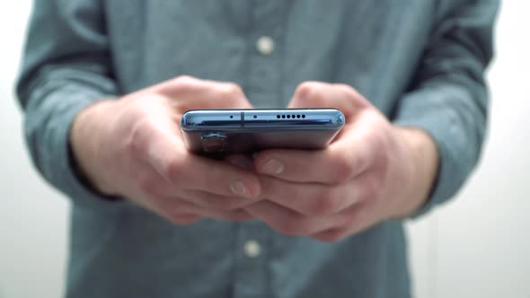 Modern young man typing a message on a smartphone. 