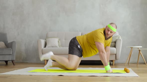 Man in Yellow Sportswear Doing Legs Lifting Exercises on Mat on Knees at Home