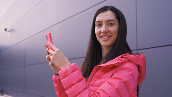 Girl Holding Her Smartphone Smiling at Camera alt