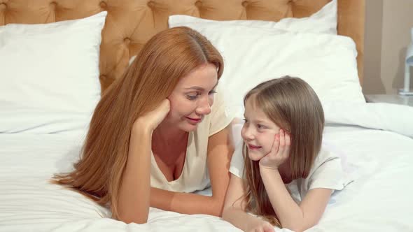 Mother and Daughter Smiling To the Camera, Lying on Bed Together alt
